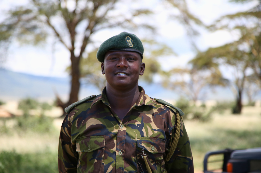 Man smiling in uniform outside.