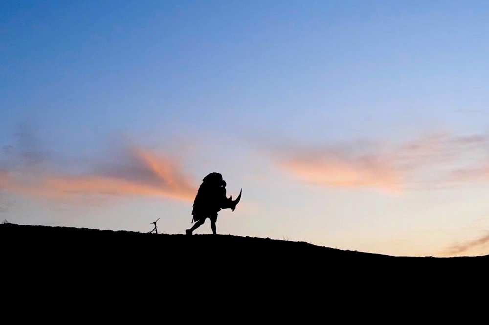 Silhouette of rhino costume running across the horizon