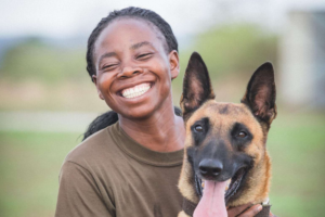 A woman smiling next to a dog.