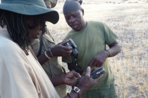 Three men looking at a camera and GPS unit