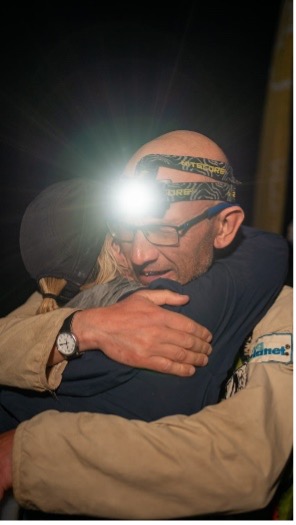 Man hugging a woman and wearing a headtorch.