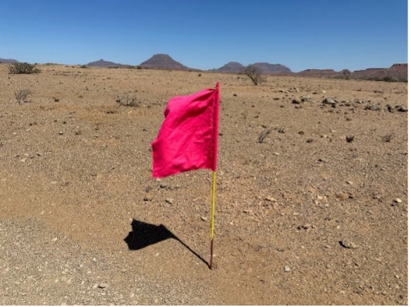 A red flag positioned in sand.
