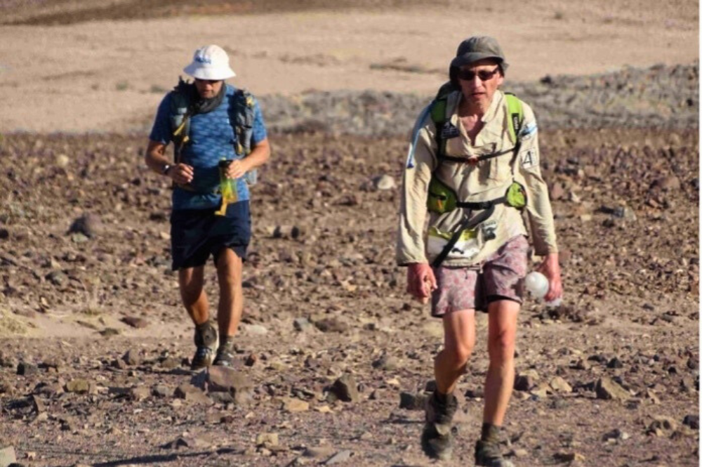 Two men walking in a hot rocky landscape.