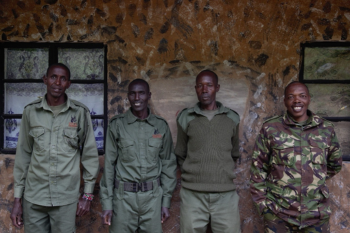 Four men standing smiling at the camera, in camo uniform.