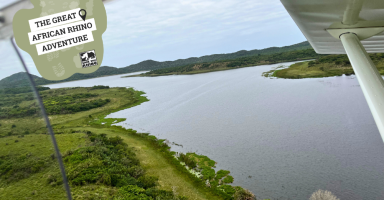 Aerial shot of a river surrounded by green areas. Text: