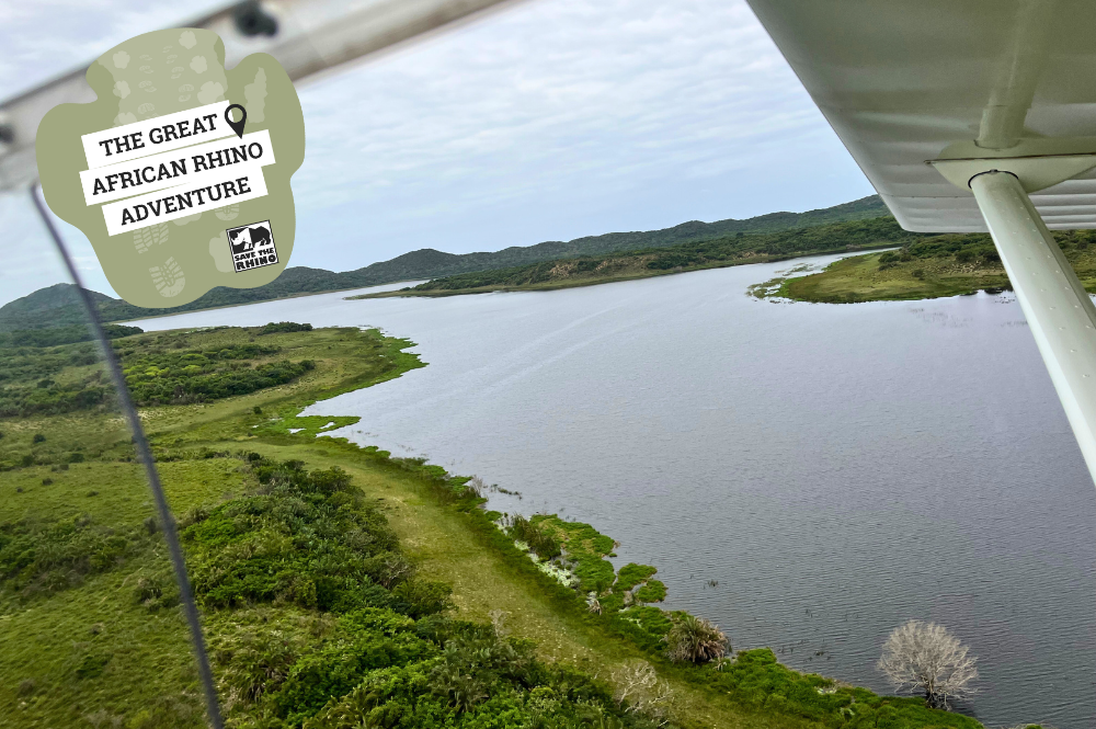 Aerial shot of a river surrounded by green areas. Text: