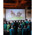 Children watching a projector video (showing gorrilas).