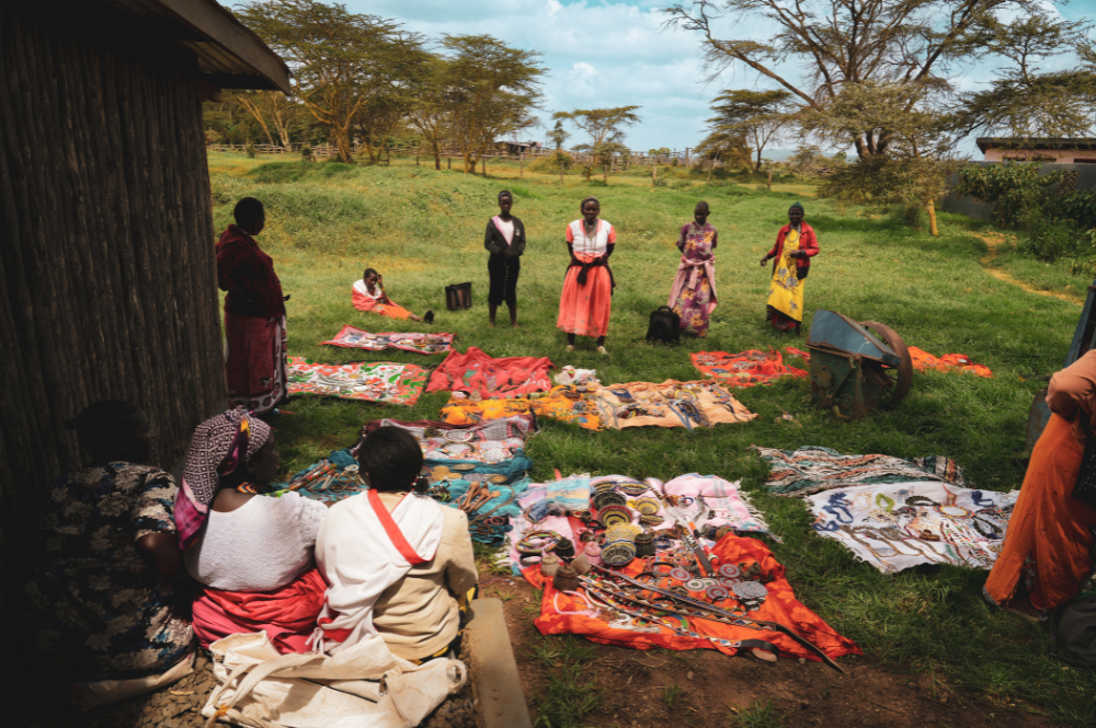 People standing and sitting outside with materials and crafts next to them