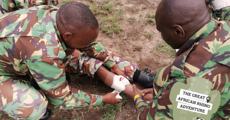 Two men in camo uniforms performing first aid on another man lying down.