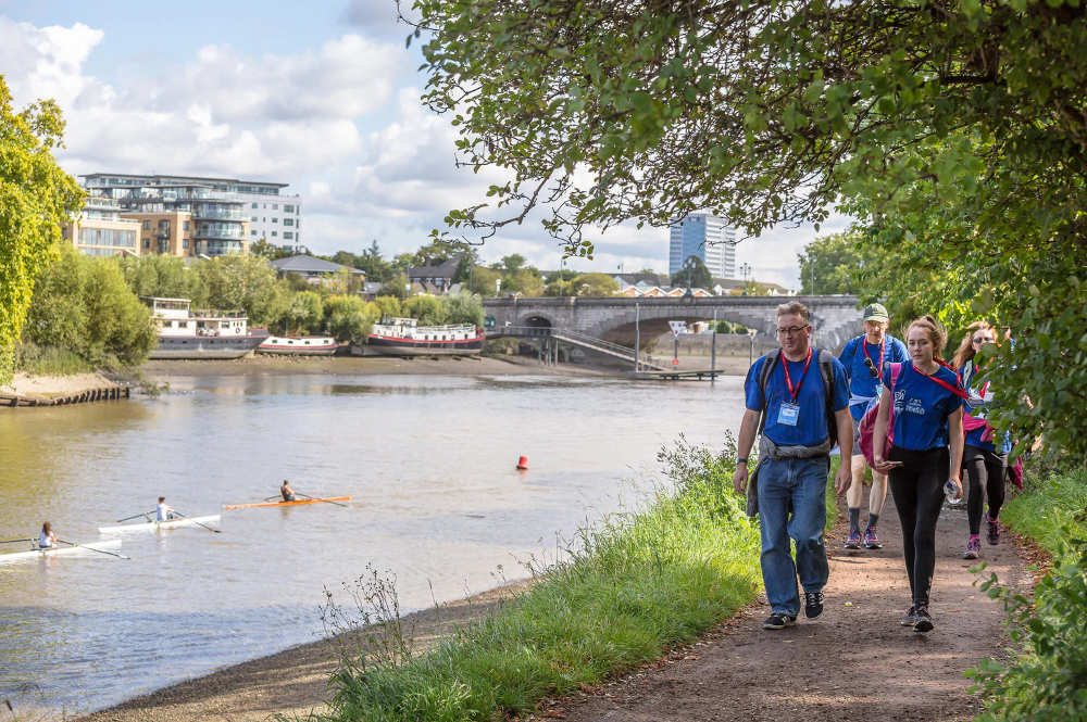 The river Thames with walkers completing a walking challenge on the path nearby.