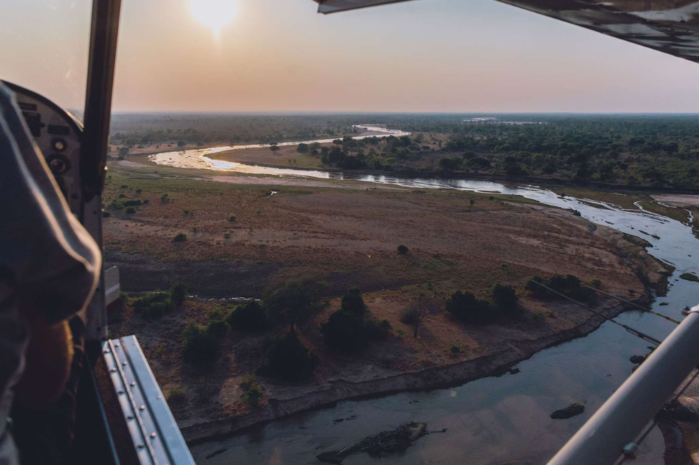 Aerial photo of a vast green landscape with a river running through trees and green habitat.