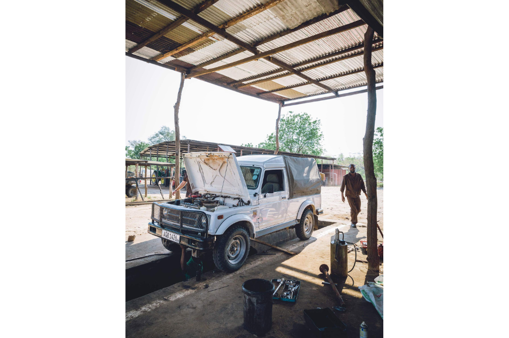 Truck with its bonnet up in a workshop, man walking by.